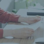 Woman reviewing employee contracts at her desk.